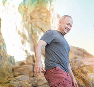 Man wearing grey shirt and red pants hiking