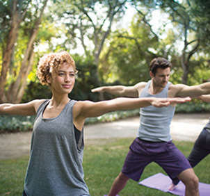 Woman and man doing Virabhadrasana (warrior pose) during yoga