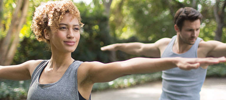 Woman and man doing Virabhadrasana (warrior pose) during yoga