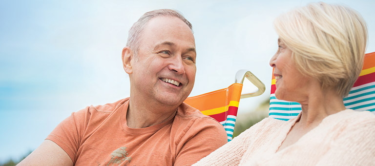 Older couple sitting on beach chairs mobile